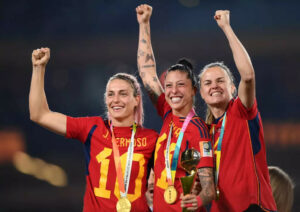 Três jogadoras espanholas a exibir o troféu  de campeãs do mundo