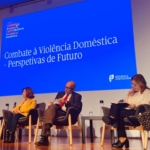 em fundo, tela com: combate à violência doméstica-perspetivas de futuro. no palco, estão sentadas, da esquerda para a direita: rosália amorim, raquel desterro, rui od carmo, marlene matos e marta silva.